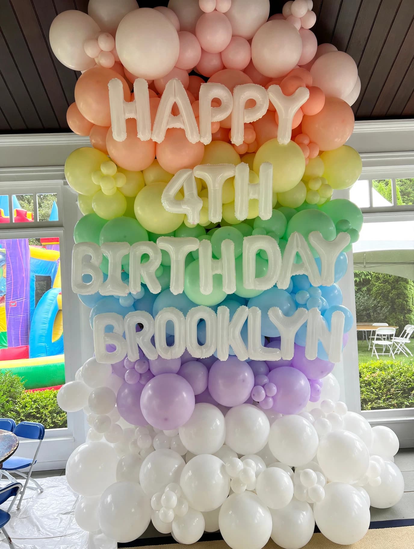 Rainbow-colored balloon wall with Happy 4th Birthday Brooklyn signage