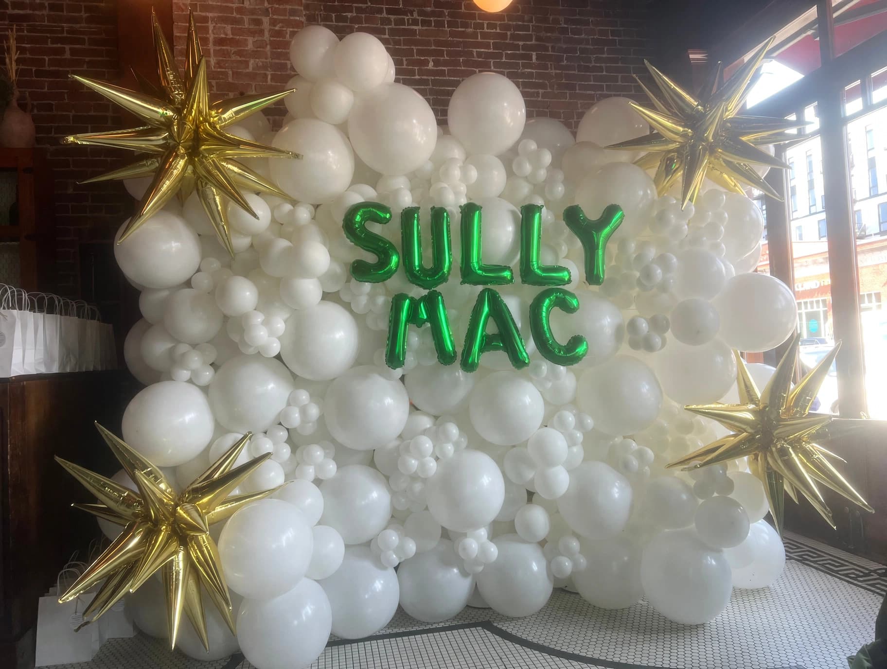 White and green branded balloon wall for SULLY MAC
