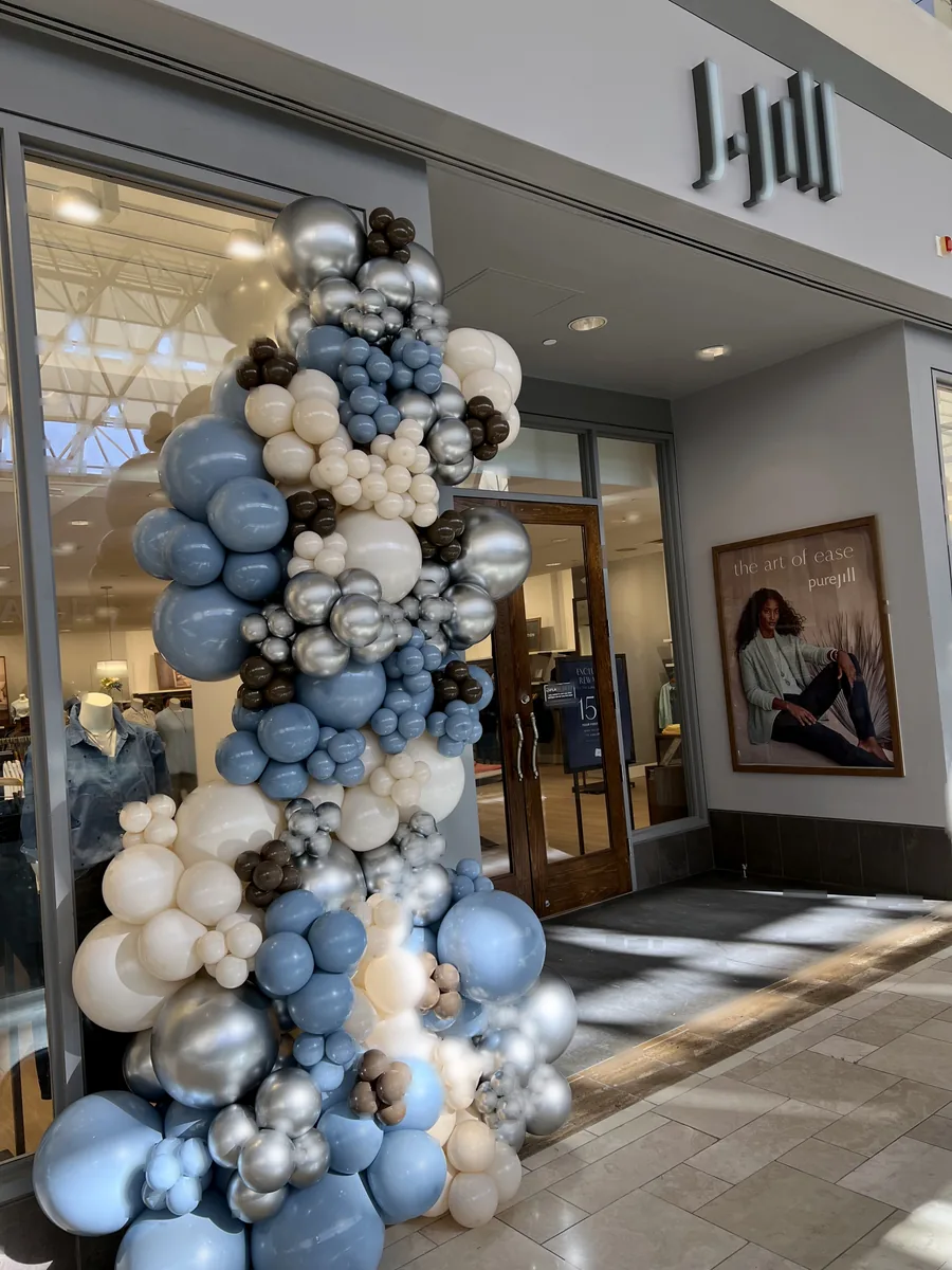 Blue, white, and silver organic balloon column outside a J.Jill retail storefront